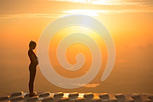 Pregnant woman sunset silhouette on top of a high-rise.