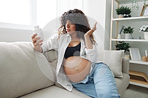 Pregnant woman surprise blogger takes vitamins and medicines sitting on the couch at home freelancer in the last month
