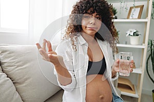 Pregnant woman surprise blogger takes vitamins and medicines sitting on the couch at home freelancer in the last month