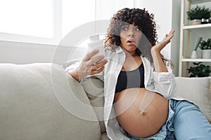 Pregnant woman surprise blogger takes vitamins and medicines sitting on the couch at home freelancer in the last month