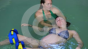 Pregnant woman in swimming pool with trainer