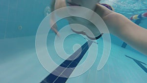 Pregnant woman swims underwater in the pool.