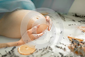 Pregnant woman takes a bath with milk, lavender herbs and orange slices