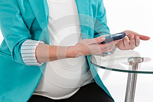 Pregnant woman taking a blood sample from her finger for glucose level