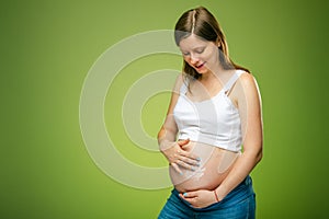 Pregnant woman taking care of hear belly skin and using special moisturizer for the skin against stretches.