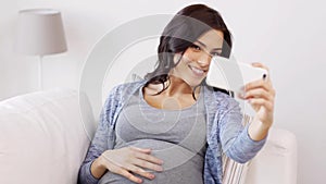 Pregnant woman taking selfy by smartphone at home