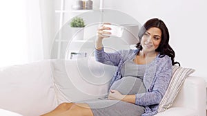 Pregnant woman taking selfy by smartphone at home