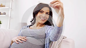Pregnant woman taking selfy by smartphone at home