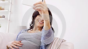 Pregnant woman taking selfy by smartphone at home