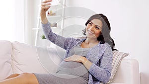 Pregnant woman taking selfy by smartphone at home