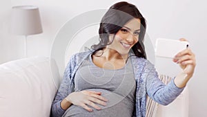 Pregnant woman taking selfy by smartphone at home