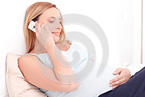 Pregnant woman talking per mobile phone in bed
