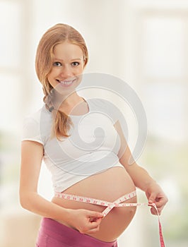 Pregnant woman with tape measuring her belly