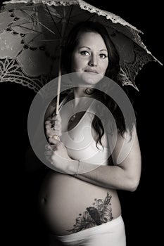 Pregnant woman with a tattoo looking holding an umbrella black