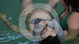 Pregnant woman with therapist in pool
