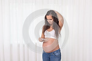 Pregnant woman with a thermometer in bedroom. Pregnancy health and medcine contest. Illness, cold, flu, allergy