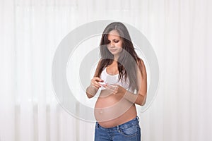 Pregnant woman with a thermometer in her bedroom. Pregnancy health and medcine contest. Illness, flu, allergy