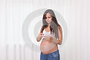 Pregnant woman with a thermometer in her bedroom. Pregnancy health and medcine contest. Illness, flu, allergy photo