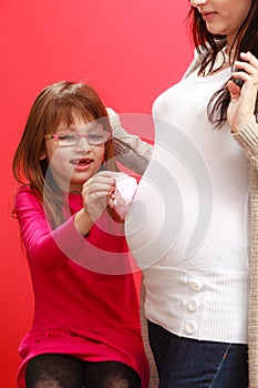 Pregnant woman with toddler girl holding baby shoes