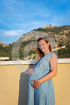 Pregnant woman touching the belly and looking at the camera