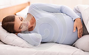 Pregnant Woman Touching Belly Resting Lying In Bed At Home