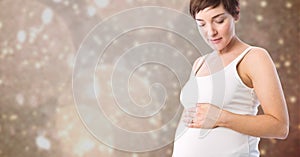 Pregnant woman touching her belly against defocused background