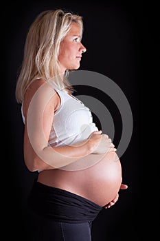 Pregnant woman touching her belly with hands.
