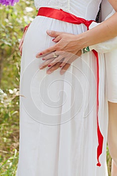 Pregnant woman touching her belly with hands