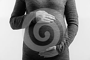 Pregnant woman touching her belly with hands, on white background