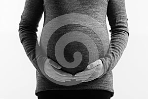 Pregnant woman touching her belly with hands on white background