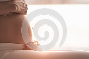 Pregnant woman touching her belly at home