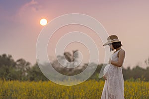 Pregnant woman touching her big belly and walking in the meadow