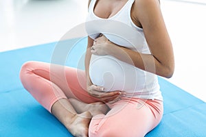 Pregnant woman touching her stomach while exercising