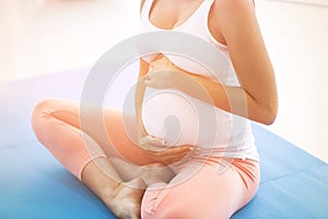 Pregnant woman touching her stomach while exercising