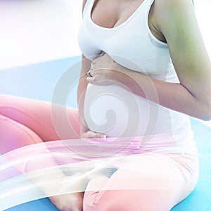 Pregnant woman touching her stomach while exercising