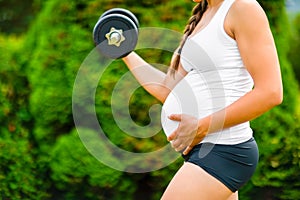 Pregnant Woman Touching Stomach While Exercising With Dumbbell