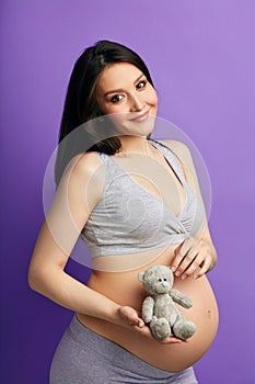 Pregnant woman with toy teddy bear. Young woman expecting a baby.