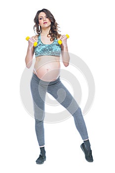 Pregnant woman training with dumbbells to stay active. Pregnant woman practicing fitness and working out during