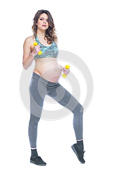 Pregnant woman training with dumbbells to stay active. Pregnant woman practicing fitness and working out during