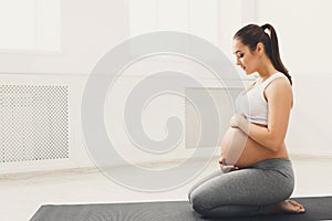 Pregnant woman training yoga in lotus pose