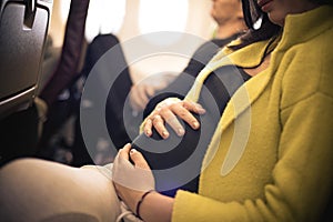 Pregnant woman traveling with airplane. Close up.