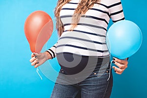 Pregnant woman tries to guess the boy or girl. Balloons as symbol of boy and girl.