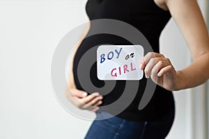 A pregnant woman is trying to guess whether it is a boy or a girl. Choosing a baby name. Concept of pregnancy, motherhood