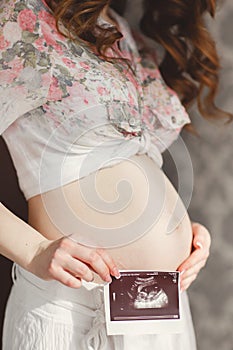 Pregnant woman with ultrasound picture in his hand.