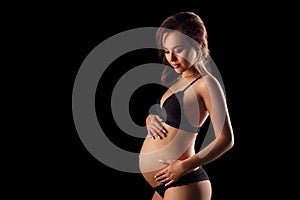 Pregnant woman in underwear on black background concept of motherhood