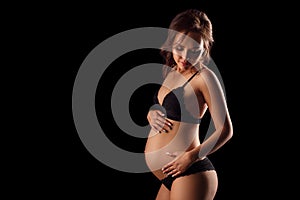 Pregnant woman in underwear on black background concept of motherhood