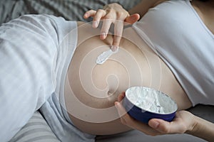 Pregnant woman uses the cream for stretch marks on belly