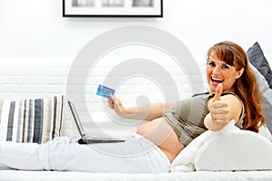 Pregnant woman using credit card to shop from net