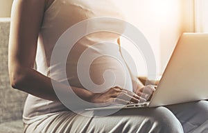 Pregnant Woman Using Laptop and Sitting on Sofa.