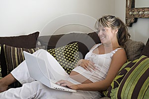 Pregnant Woman Using Laptop On Sofa